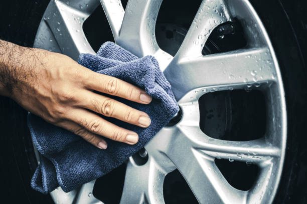 Hand is wipe the alloy wheel with a microfiber cloth stock photo