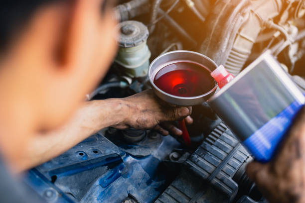 Hand mechanic in repairing car , Gear oil change, Filling the oil through the hose. Car maintenance station. Red gear oil. stock photo