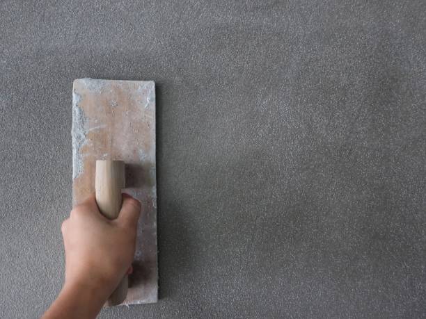 Hand of a man holds a trowel for plastering a cement wall stock photo