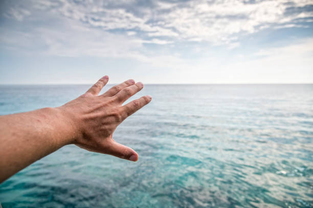 Hand of a man reaching out the horizon line stock photo