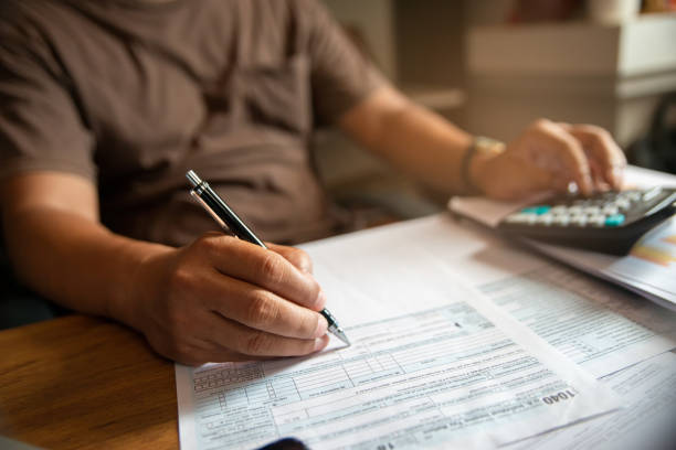 hand of Accountant calculate tax return and work at home, Asian businessman planning budget, account balance sheet, and personal income for worker have income under us law. stock photo