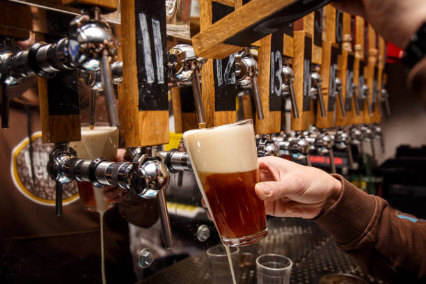 Hand of bartender pouring a red ale from tap. stock photo