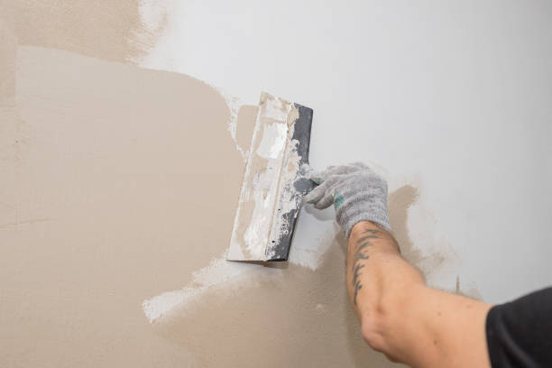 hand of builder worker plastering at wall.Renovation workers hand plastering the wall.Construction finishing works.work aligns with a spatula wall.process of applying layer of putty trowel stock photo
