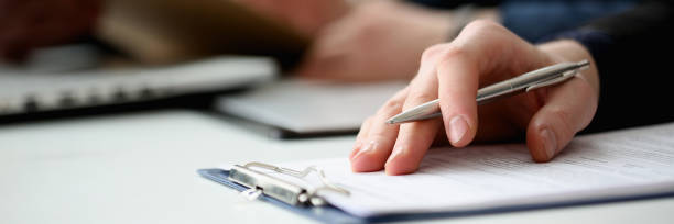 Hand of businessman signing document with pen Hand of businessman in suit filling and signing with silver pen partnership agreement form clipped to pad closeup. Management training course, some important document, team leader ambition concept form document stock pictures, royalty-free photos & images