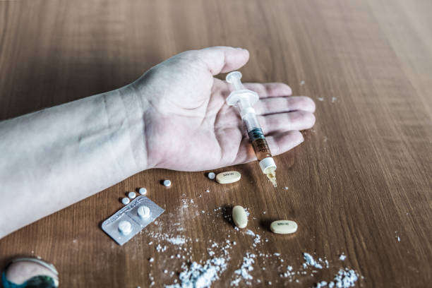 Hand of drug abuser on the floor with drugs, heroin and cocain. stock photo