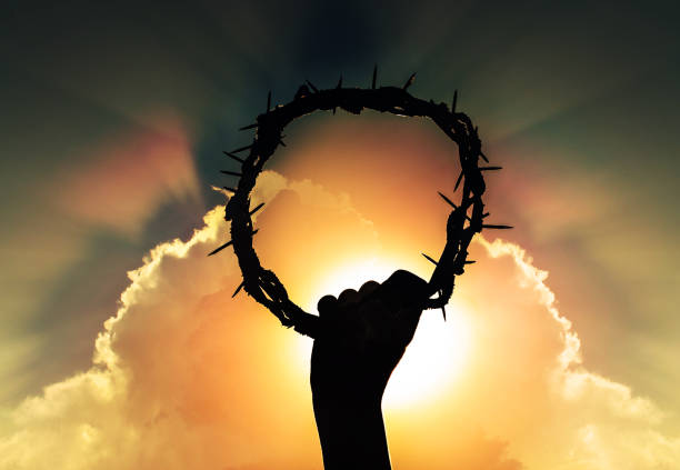 hand of Jesus christ with sky and rising sun, holding crown of thorns, critsão symbol of rebirth, faith and easter stock photo