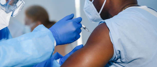 ręka personelu medycznego w niebieskiej rękawiczce wstrzykiwanie coronavirus covid-19 szczepionki w strzykawce szczepionki do mięśni ramię african american man do koronawirusa covid-19 szczepień - covid vaccine zdjęcia i obrazy z banku zdjęć