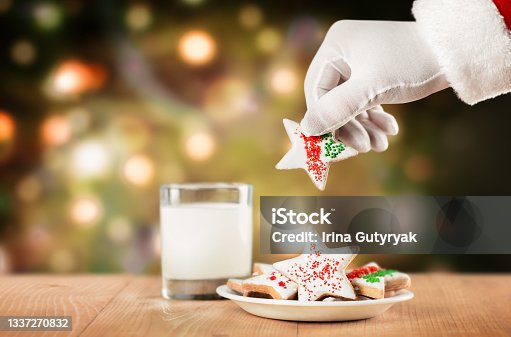 istock hand of santa claus and cookies with milk 1337270832