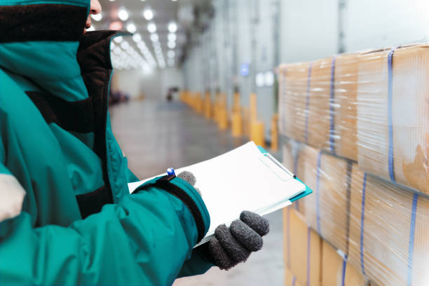 Hand of worker with clipboard checking goods in freezing room or warehouse. Export-Import Logistics system concept stock photo