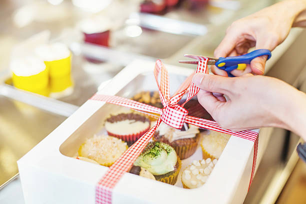 Hand packing many kinds of cupcakes a present for wedding or birthday (soft  focus on fingers holding a ribbon) cake parcels stock pictures, royalty-free photos & images