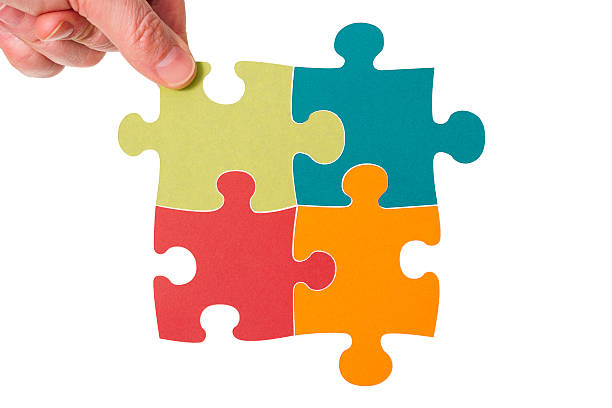 Hand places blank colourful jigsaw piece amongst others stock photo