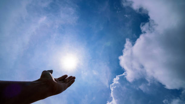 hand praying for blessing from god on sun and clouds background,Christian Religion concept stock photo