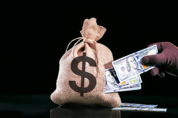 Hand pulls money, dollars out of the bag. Stealing money stock photo