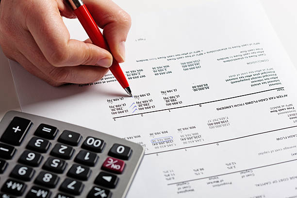 Hand puts check marks on financial document, calculator standing by A man's hand checks a document, adding check marks with a ballpoint pen, a calculator standing by. Could be an audit, home or office finances being checked so carefully. accounting ledger stock pictures, royalty-free photos & images