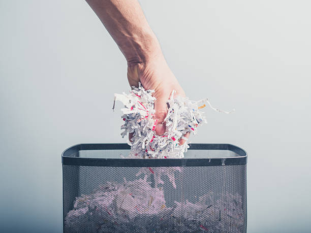 Hand putting shredded paper in basket stock photo