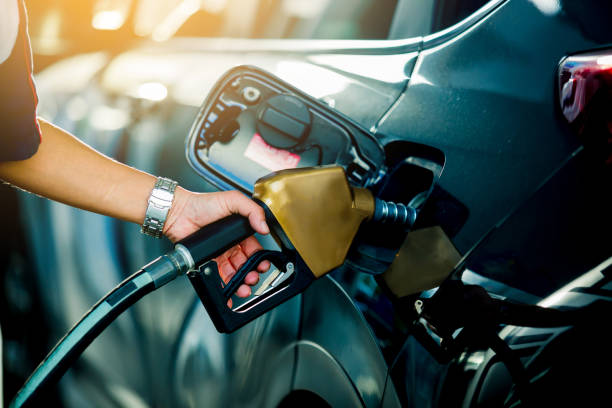 hand refilling the car with fuel at the refuel station - gasoline imagens e fotografias de stock