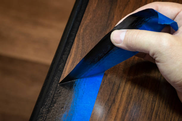 Hand removing blue painter's tape stock photo