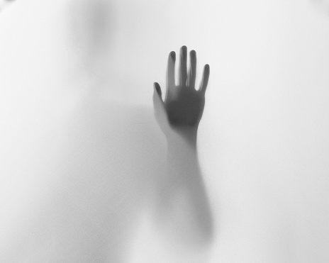 Hand silhouette behind the frosted glass, mystery Halloween photography
