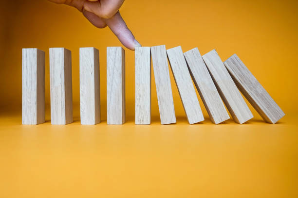 Hand stopping wooden domino business crisis effect or risk protection concept. stock photo