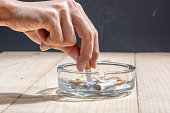 istock Hand stubbed out cigarette in a transparent ashtray 1159981306