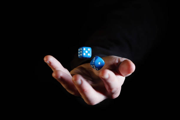 Hand throwing dice cubes in the air against black background Hand throwing dice cubes in the air against black background dice photos stock pictures, royalty-free photos & images