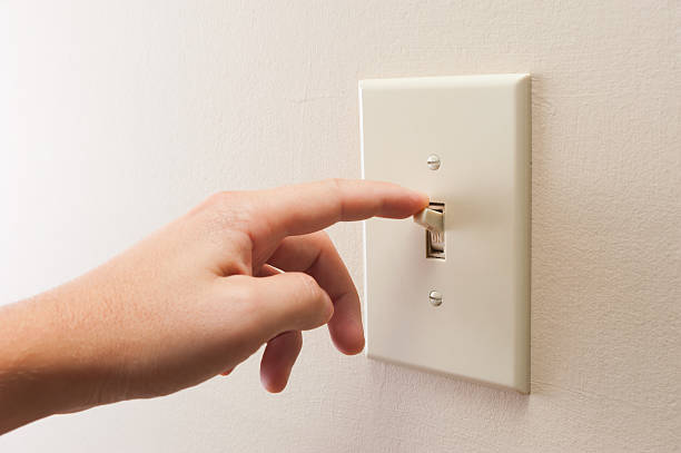 Hand turning wall light switch off stock photo
