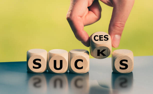 Hand turns a cube and changes the word "sucks" to "success". stock photo
