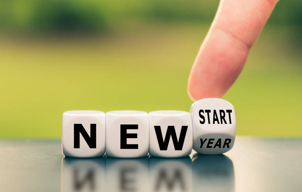 Hand turns a dice and changes the expression "new year" to "new start". stock photo