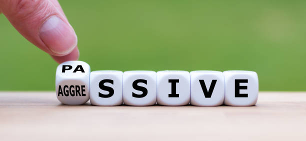 Hand turns a dice and changes the word "passive" to "aggressive", or vice versa. stock photo
