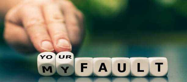 Hand turns dice and changes the expression "my fault" to "your fault". stock photo