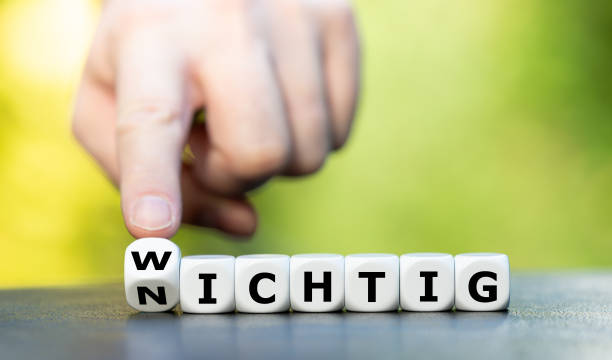 Hand turns dice and changes the German word "nichtig" (unimportant) to "wichtig" (important). stock photo