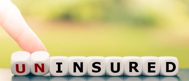 Hand turns dice and changes the word "uninsured" to "insured". stock photo