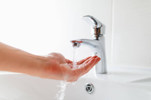 hand under faucet with water stream stock photo