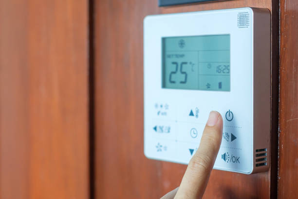 hand using remote controller for adjust Air conditioner inside the room of hotel or home stock photo
