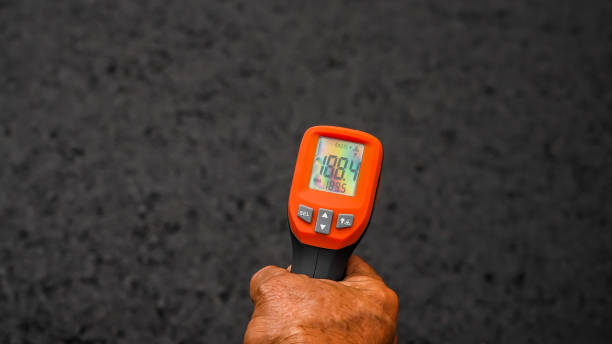 Hand with close up from thermometer is showing how hot is asphalt after around 20 minutes after is flattered stock photo
