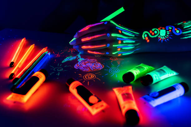 Hand with fluorescent ethnic pattern holding neon pencil. Fluorescent paint and pencil are on the table. Body Art concept Hand with fluorescent ethnic pattern holding neon pencil. Fluorescent paint and pencil are on the table. Body Art concept paint neon color neon light ultraviolet light stock pictures, royalty-free photos & images