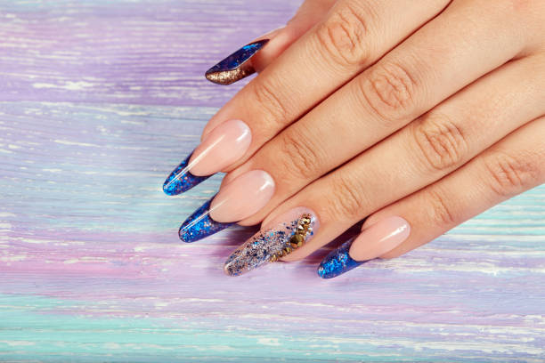 Hand with long artificial blue french manicured nails Hand with long artificial blue french manicured nails decorated with crystals artificial nail stock pictures, royalty-free photos & images