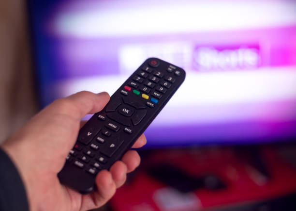 Hand with TV remote and screen on background stock photo