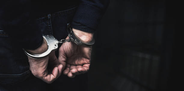 handcuffed arrested man behind prison bars. copy space handcuffed arrested man behind prison bars. copy space latvia stock pictures, royalty-free photos & images