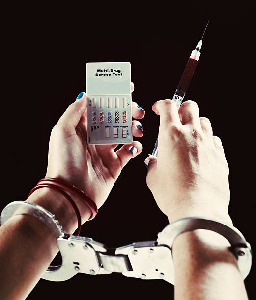 handcuffed female addict with blood-filled syringe and drug test kit - needle spiking stockfoto's en -beelden