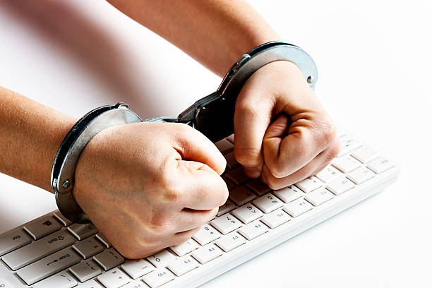 Handcuffed fists hit computer keyboard in frustration stock photo