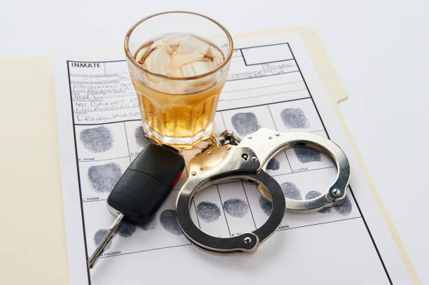 Handcuffs, keys and glass of alcohol on ice on top of finger print card stock photo