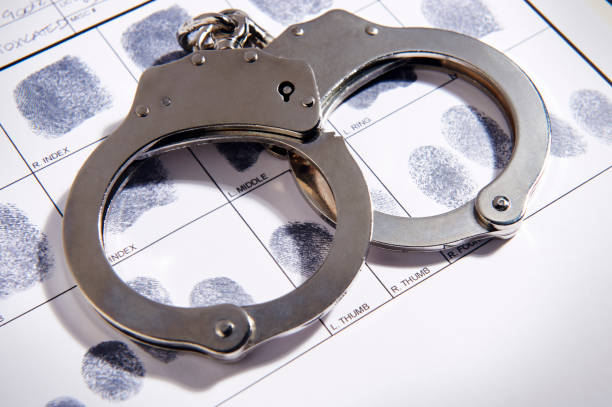 Handcuffs laying on top of fingerprint chart in file stock photo