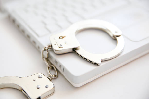 handcuffs on keyboard - prision imagens e fotografias de stock