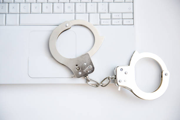 handcuffs on laptop keyboard - prision imagens e fotografias de stock