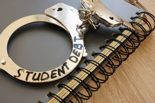 Handcuffs with sign student debt and notebook. Handcuffs with sign student debt and notebook. student debt stock pictures, royalty-free photos & images
