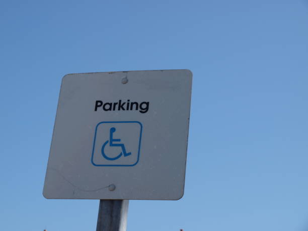 A handicap disability parking sign against a blue sky stock photo