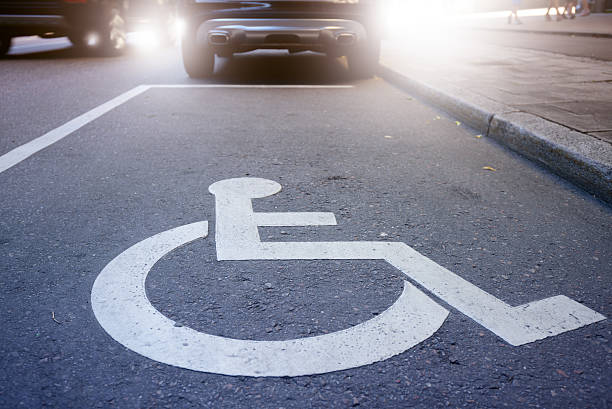 Handicap symbol on road, traffic and pedestrians in background stock photo