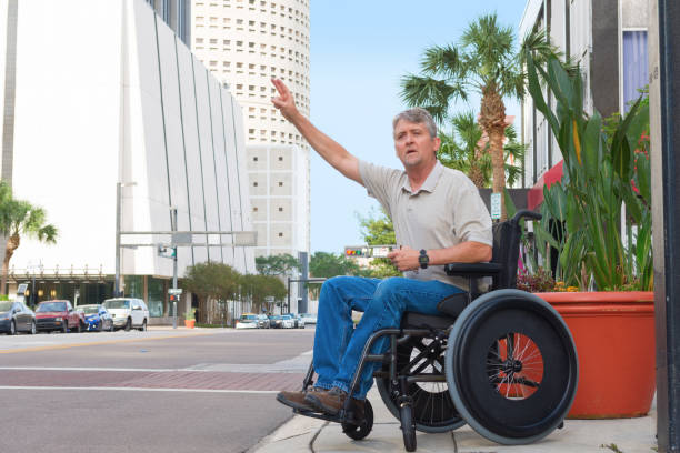 Handicapped man in a wheelchair hailing a taxi in the city stock photo