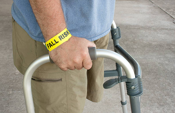 Handicapped Man Wearing A Fall Risk Bracelet A handicap man wearing a fall risk bracelet around his wrist using a walker inpatient stock pictures, royalty-free photos & images